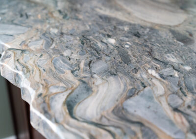 Close-up of a swirled marble countertop with gray, white, and beige veining in a kitchen setting.